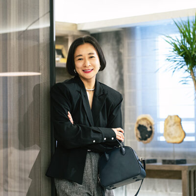 自身のショップで取り扱っているバッグを手に微笑むスタイリスト・佐藤佳菜子さん