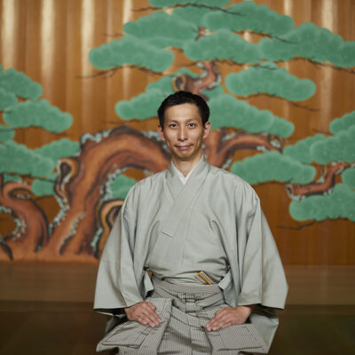 能舞台を背景に佇む能楽師・塩津圭介さん