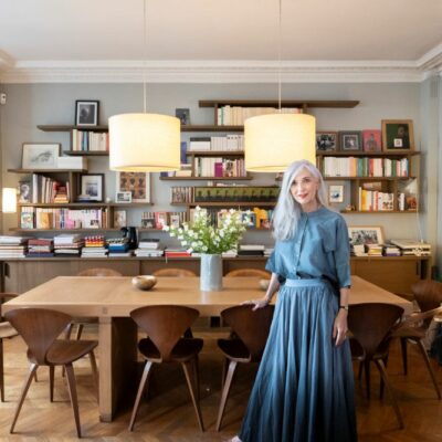 ブリジット・ラノー・レヴィさんとご自宅のリビング。デルクールデザインの本棚とキャラバンのランプが印象的