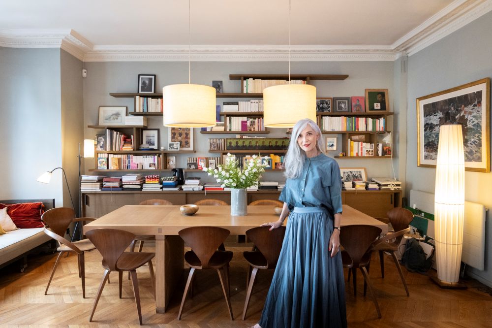 ブリジット・ラノー・レヴィさんとご自宅のリビング。デルクールデザインの本棚とキャラバンのランプが印象的