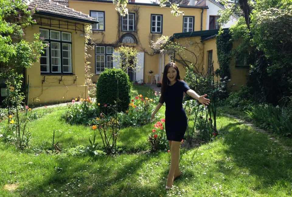 初夏の陽光が差し込むウィーンの庭園に立つ田中彩子さん
